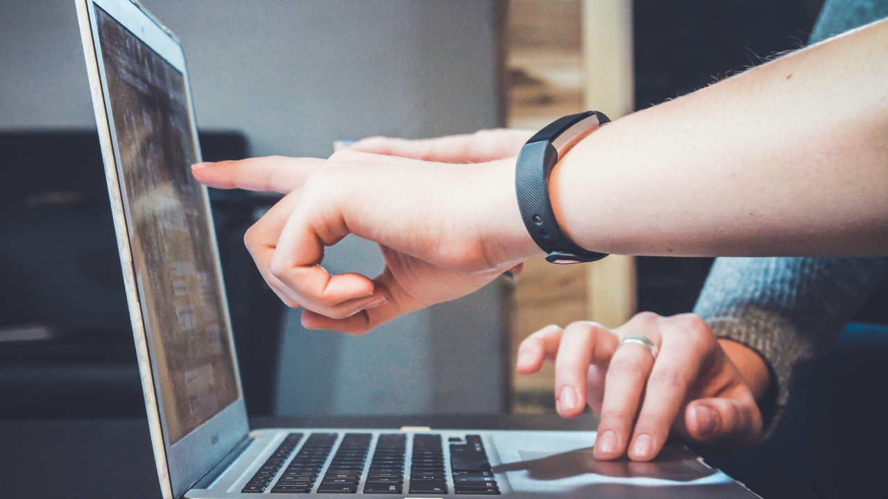 Two people pointing at a laptop screen