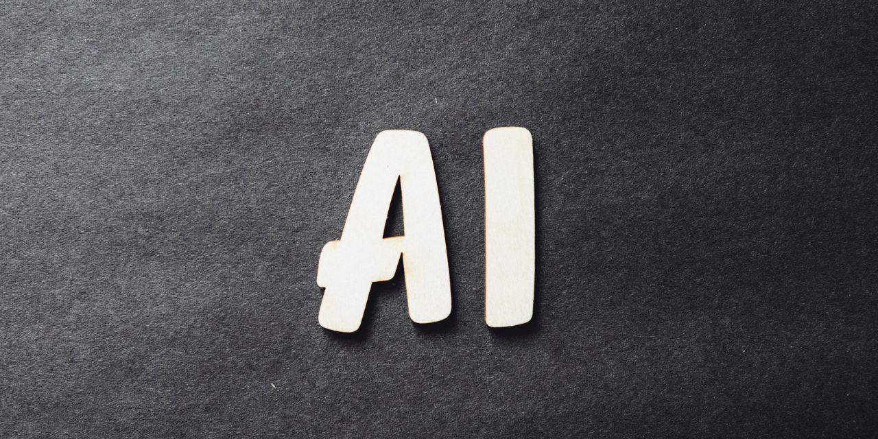 The letters 'A' and 'I' on a grey fabric background. Photo by Markus Spiske on Unsplash